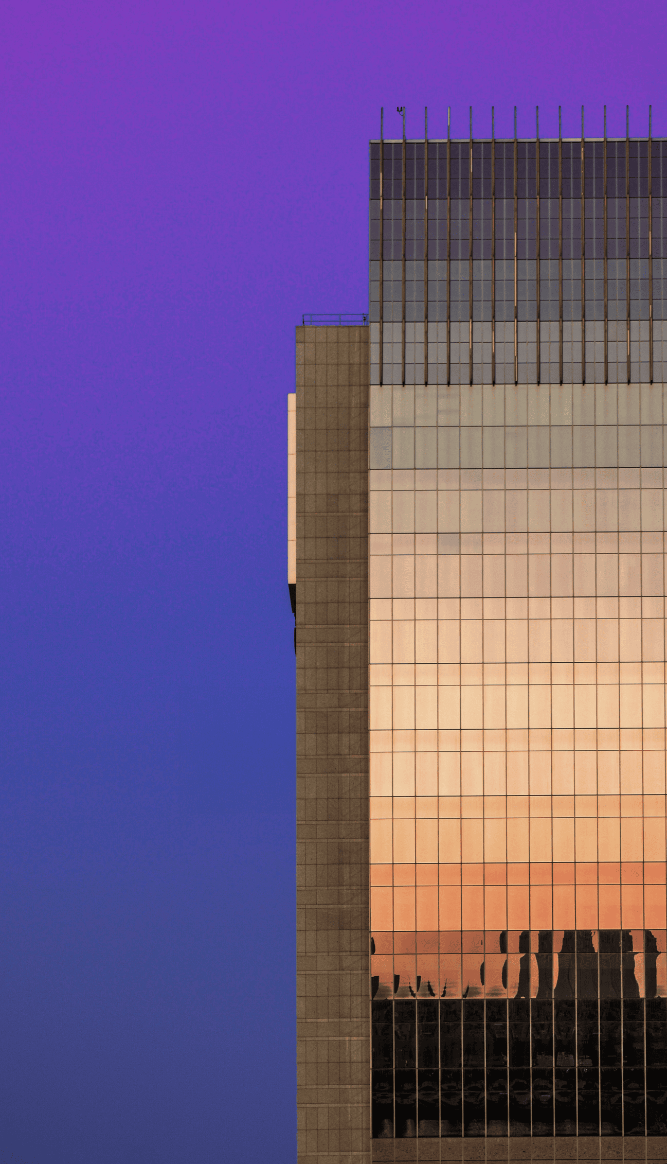 A glass office tower against a twilight sky